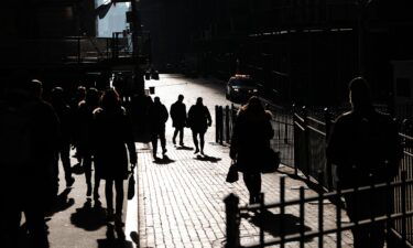 People walk along Wall Street on February 16 in New York City. Millions of Americans remained out of work because they or a loved one were sick with coronavirus symptoms in late January and early February