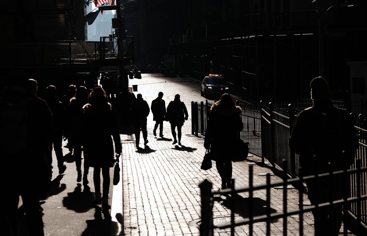 <i>Spencer Platt/Getty Images</i><br/>People walk along Wall Street on February 16 in New York City. Millions of Americans remained out of work because they or a loved one were sick with coronavirus symptoms in late January and early February