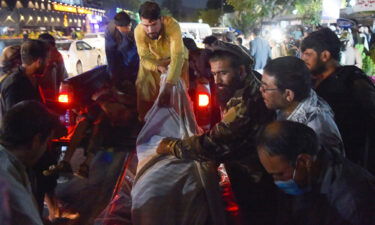 Volunteers and medical staff unload bodies from a pickup truck outside a hospital outside the airport in Kabul on August 26