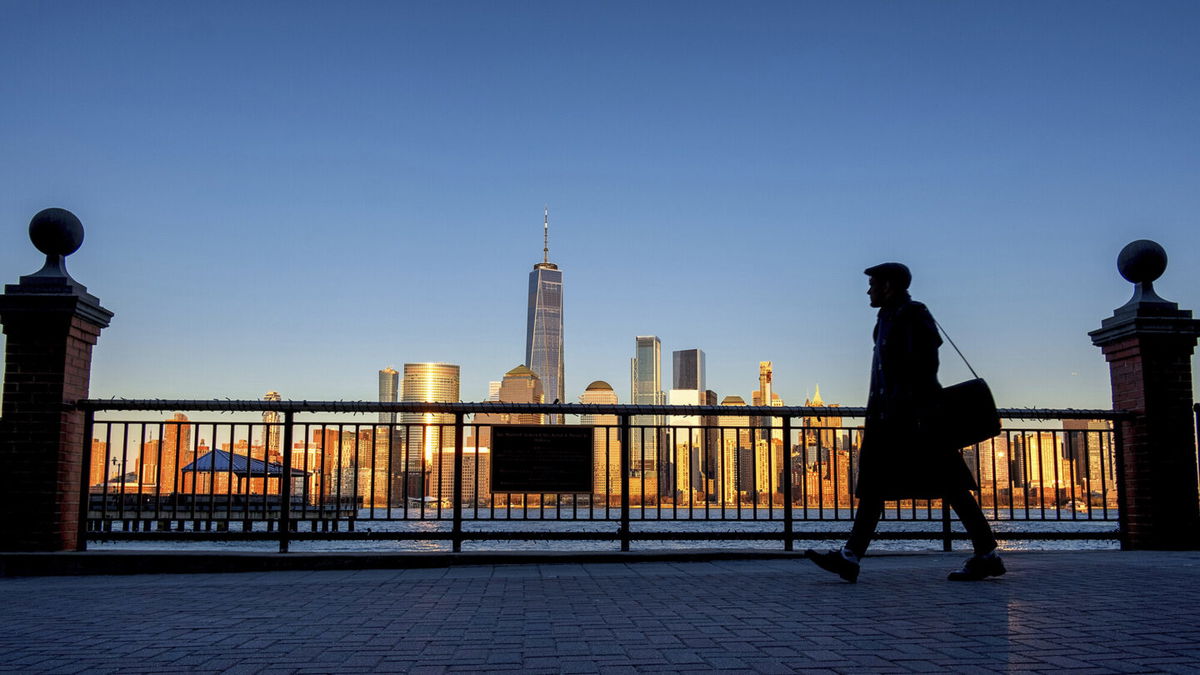 <i>J. David Ake/AP</i><br/>An evening commuter is silhouetted against the glistening New York City skyline at sunset as he walks along Hudson River shoreline in Jersey City