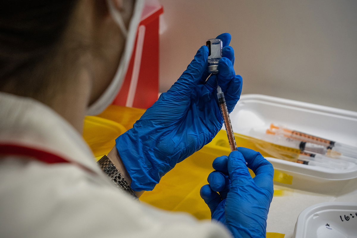 <i>Carl Court/Getty Images</i><br/>Covid vaccine gives Pfizer sales and profits a big boost.  A nurse here prepares syringes with the Pfizer coronavirus booster vaccination on January 20