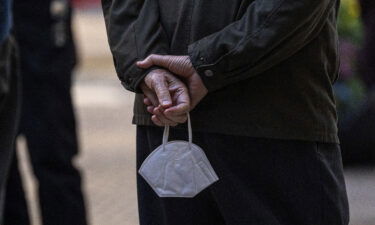 A customer waiting to enter a restaurant holds a protective mask in San Francisco