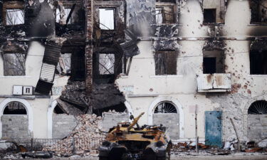 A burned military vehicle in front of a destroyed building in Uglegorsk