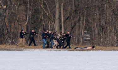 Police approach a person of interest on the south bank of the North River in Bridgewater