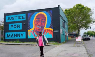 A woman walks past a mural honoring Manuel "Manny" Ellis in May 2021