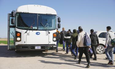 Asylum seekers board a bus to be transported to an immigration facility