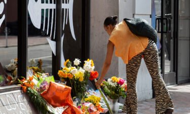 Adrian Blakemore adds flowers to a memorial honoring the victims of a shooting in Norfolk