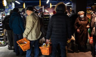Residents shopping for food and supplies queue at the checkout area of a supermarket in Kyiv