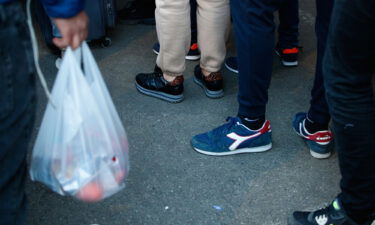 People are seen waiting in line for food at a temporary handout point in Warsaw