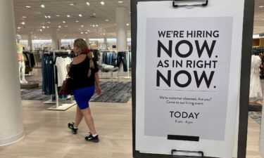 A customer walks behind a sign at a Nordstrom store seeking employees in Coral Gables