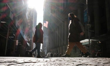 People walk along Wall Street near the New York Stock Exchange (NYSE) on March 11 in New York City. Surging oil and gas prices have raised recession alarm bells around the world. But another economic indicator is starting to look ominous: The yield curve is flattening.