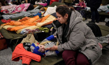 A woman feeds a child as they and other refugees from Ukraine rest at a temporary shelter in the main train station of Krakow