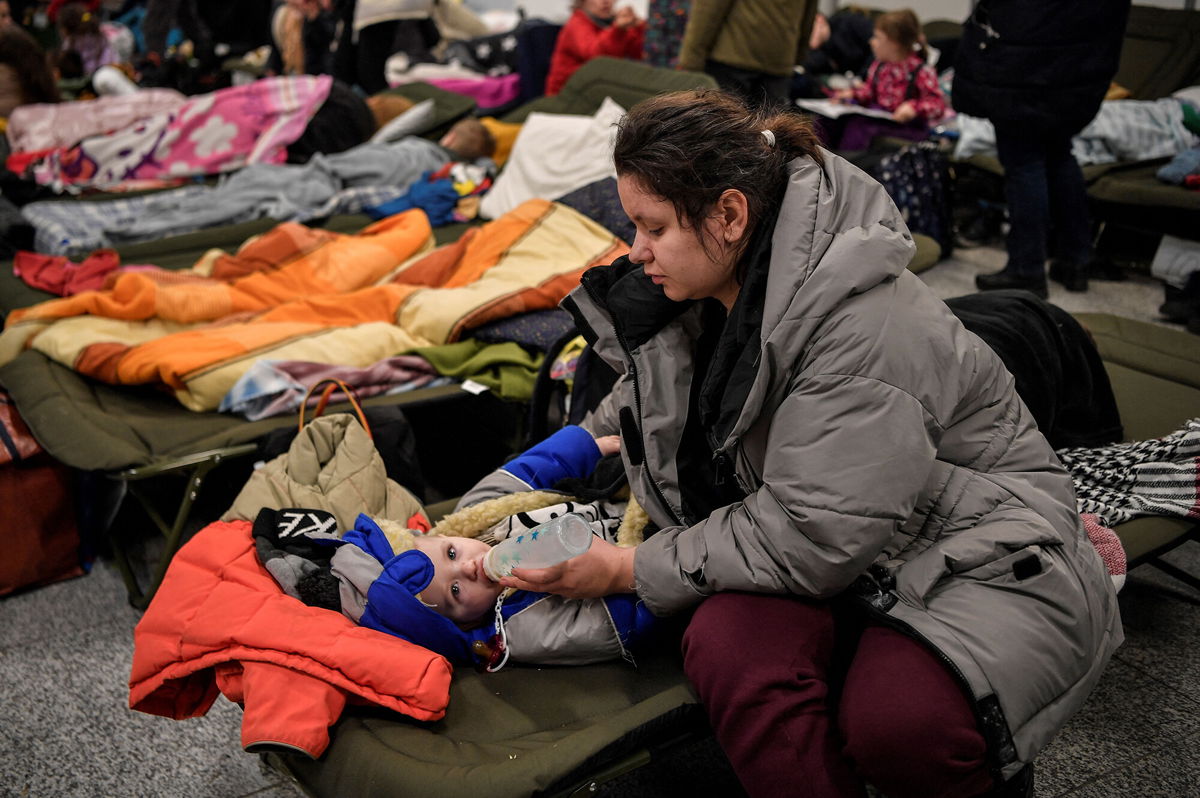<i>Louisa Gouliamaki/AFP/Getty Images</i><br/>A woman feeds a child as they and other refugees from Ukraine rest at a temporary shelter in the main train station of Krakow