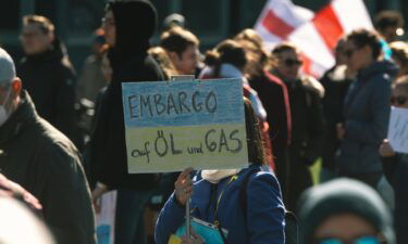 A protester holds a sign calling for an "embargo of oil and gas" during an anti-war protest in Duesseldorf