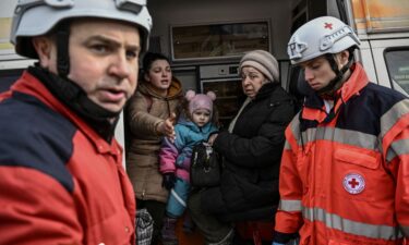 Members of the Red Cross help people who flee the city of Irpin