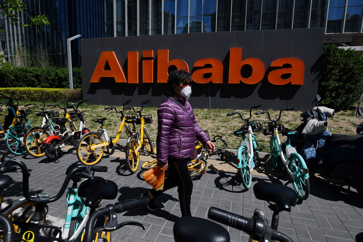 <i>Greg Baker/AFP/Getty Images</i><br/>A woman walks past an Alibaba sign outside the company's office in Beijing on April 2021. Shares of Alibaba rose more than 11% on March 22 after the company announced it was boosting the size of its share buyback program.