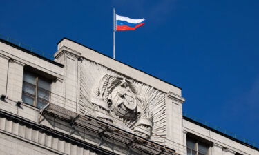 The hammer and sickle emblem beneath a Russian national flag at the State Duma building in Moscow