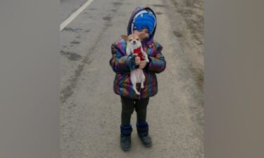 Five year old Milan keeps his spirits up with a friend's dog during stalemate traffic at a Poland checkpoint.
