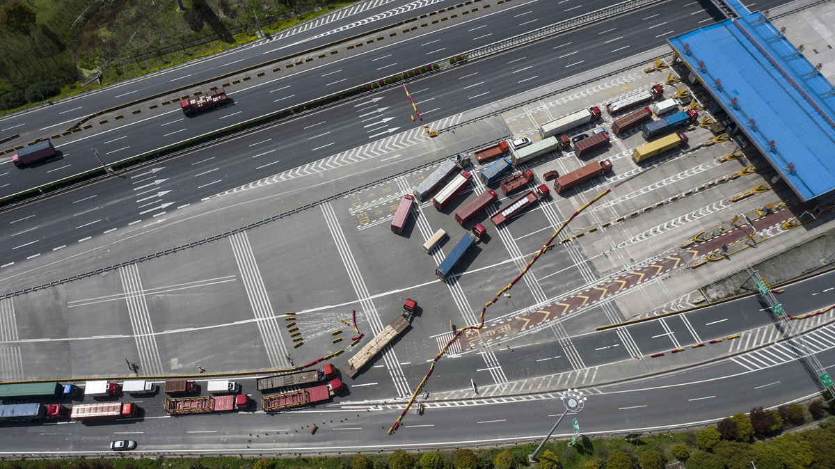 <i>Qilai Shen/Bloomberg/Getty Images</i><br/>Trucks pass through a checkpoint on a highway leading from Shanghai