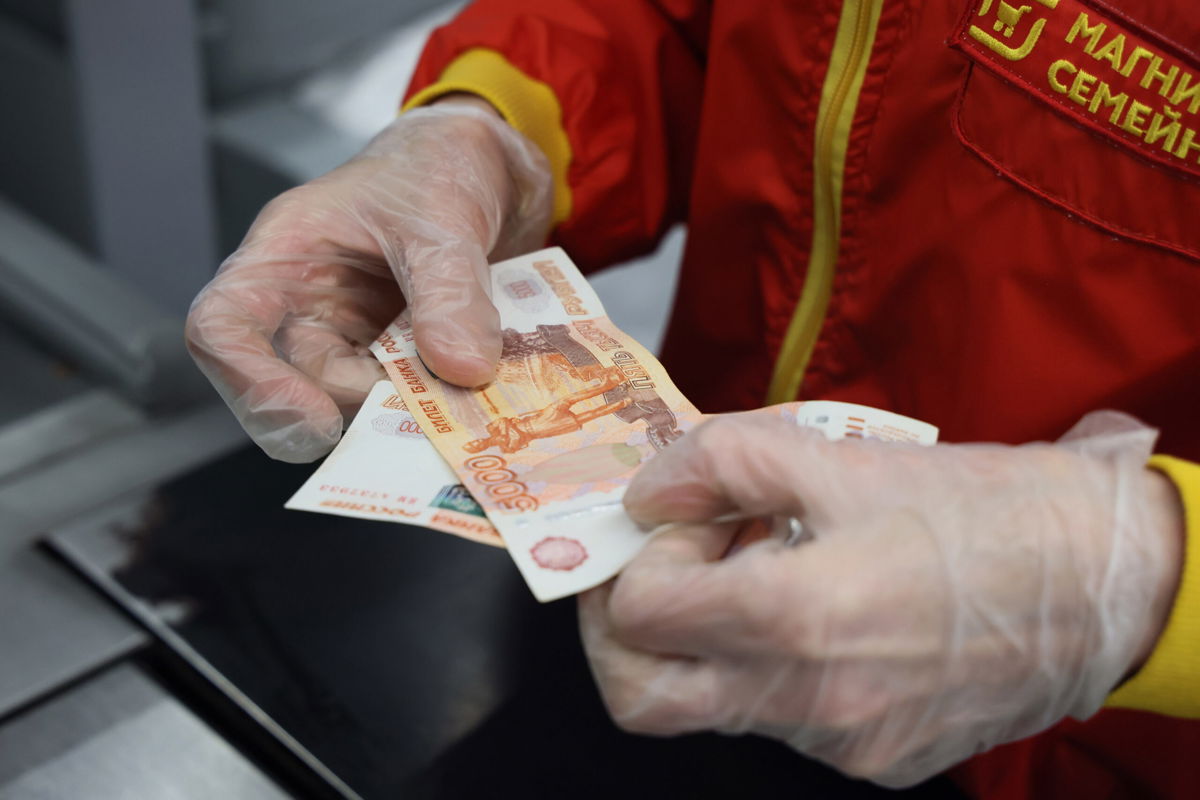 <i>Dmitry Feoktistov/TASS/Reuters</i><br/>A cashier looks at a 5000 ruble banknote at a grocery shop of the Magnit food retailer. Magnit has announced it will hold the retail margin at 5% for a number of essential products.