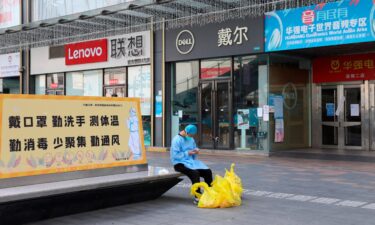 A janitor checks his phone outside closed shops in Huaqiangbei area