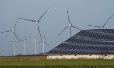 Wind turbines stand next to a hall with photovoltaic systems on the roof in Schleswig-Holstein