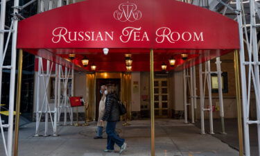 People wearing masks walk past the Russian Tea Room on October 17