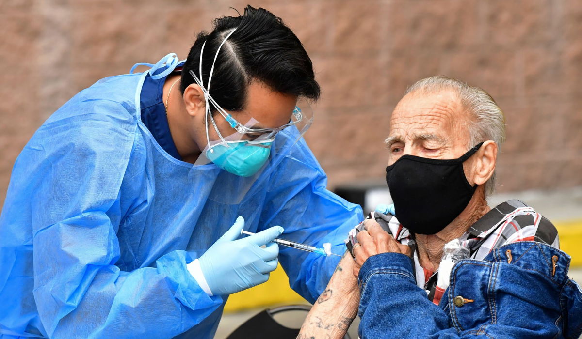 <i>FREDERIC J. BROWN/AFP/AFP via Getty Images</i><br/>Registered Nurse Angelo Bautista administers the Moderna Covid-19 vaccine during the distribution of vaccines to seniors above the age of 65 who are experiencing homelessness at the Los Angeles Mission.