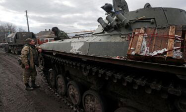 Troops in uniforms without insignia are seen next to an armored vehicle with the symbol "Z" painted on its side