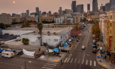 An aerial view of homeless encampments in Skid Row as smoke from California wildfires obscures the setting sun and skyline in 2021 in Los Angeles