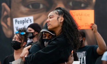 Two women embrace in front of a mural of George Floyd following the guilty verdict the trial of Derek Chauvin on April 20