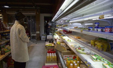 A customer stands near partially emptied shelves at a supermarket in Shanghai