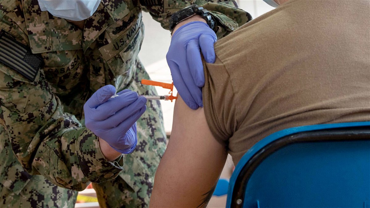 <i>Seaman Jackson Adkins/US Navy</i><br/>Hospital Corpsman 3rd Class Joseph Casassa administers a Covid-19 vaccine to Logistics Specialist Seaman Rix Zhang.