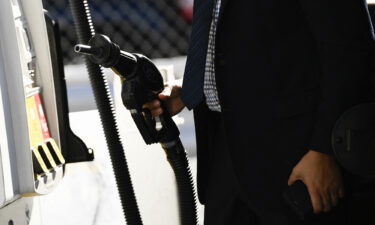 A customer returns a nozzle to a pump after fueling  gasoline into a sport utility vehicle (SUV) at a Shell gas station in the Chinatown neighborhood of Los Angeles