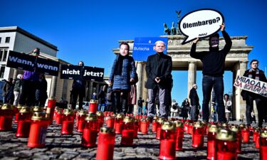 Activists wearing masks with the likenesses of Chancellor Scholz (M)