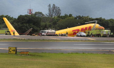 Firefighters work at the scene where a Boeing 757-200 cargo aircraft operated by DHL made an emergency landing before skidding off the runway and splitting