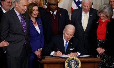 President Joe Biden signs the Postal Service Reform Act into law during an event with (from left) Sen. Gary Peters (D-MI)