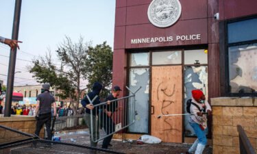 Protesters use a barricade to try and break the windows of the Third Police Precinct on May 28