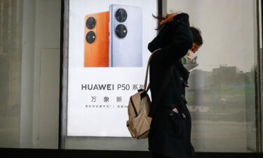 A woman walks past a Huawei advertisement in Beijing