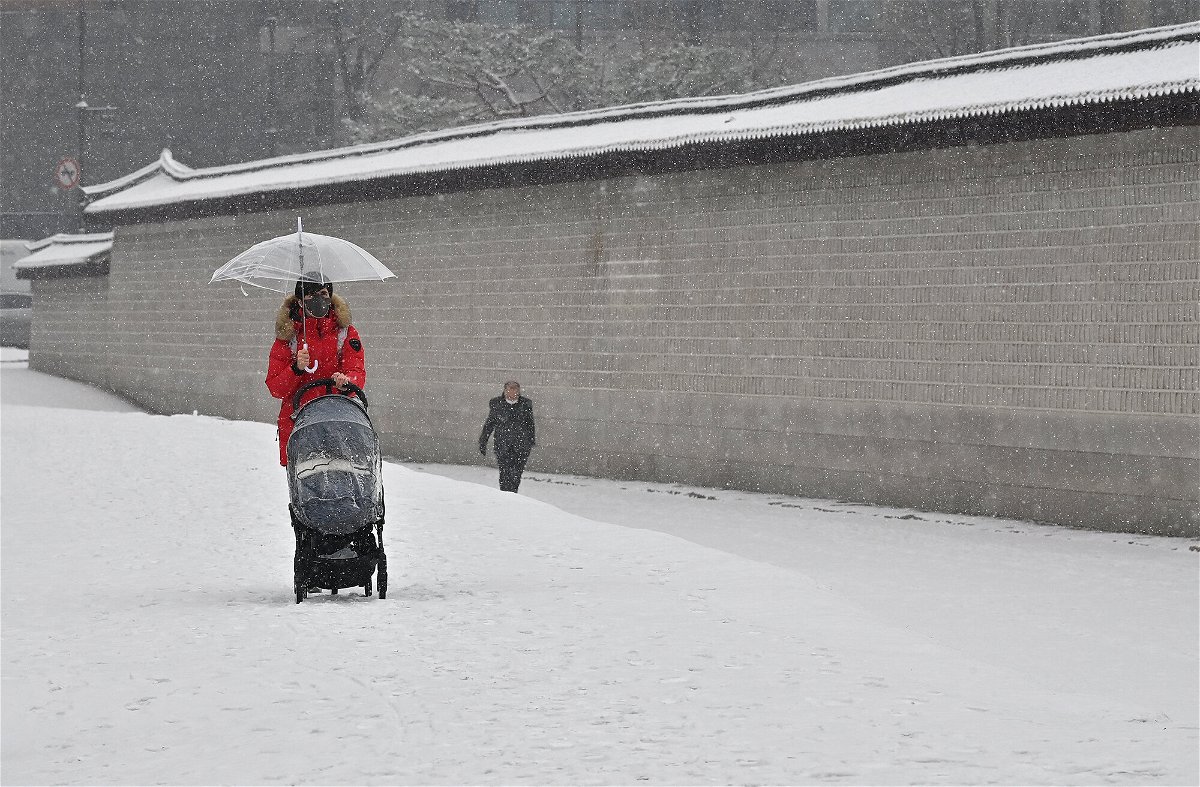 <i>Jung Yeon-je/AFP/Getty Images</i><br/>A woman wheels a pushchair along a snow-covered street in central Seoul on January 19. While America finds itself in the middle of the cost scale