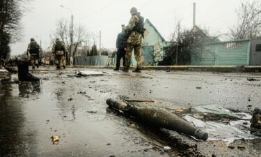 Ukrainian soldiers inspect the wreckage of a destroyed Russian armored column on the road in Bucha