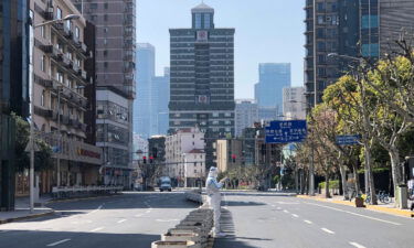 A worker in protective overall stands in the middle of empty streets in a lockdown area in the Jingan district of western Shanghai