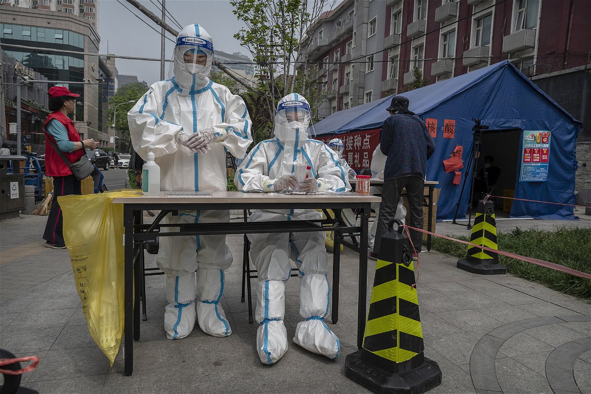 <i>Kevin Frayer/Getty Images</i><br/>Health workers wait to give local residents nucleic acid tests to detect Covid-19 at a makeshift testing site in Chaoyang District on April 25