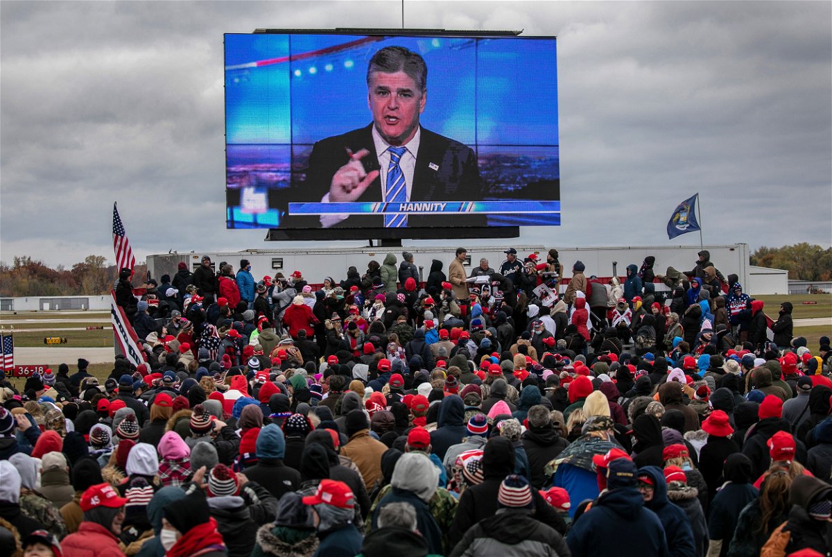 <i>John Moore/Getty Images</i><br/>Supporters of former President Donald Trump watch a video featuring Fox host Sean Hannity ahead of Trump's arrival at a campaign rally in Michigan in October 2020.