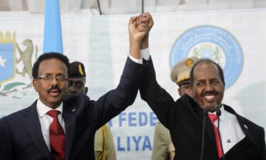 Somalia's newly elected president Hassan Sheikh Mohamud (R) holds hands with incumbent president Mohamed Abdullahi Mohamed (L) after winning the elections in Mogadishu
