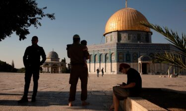 An Israeli police officer stands guard as a religious Jew in Army uniform visits the Temple Mount