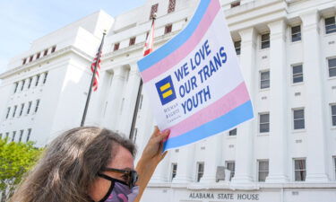 A woman holds a sign that reads "We Love Our Trans Youth" during a rally in Montgomery