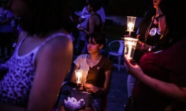 A young woman holds a candle during a candlelight vigil to honor and remember the victims of the mass shooting in Uvalde