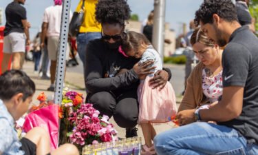A young girl comforts a person crying on May 15 at a memorial outside of a Tops Friendly Market where a mass shooter killed 10 people and wounded three.