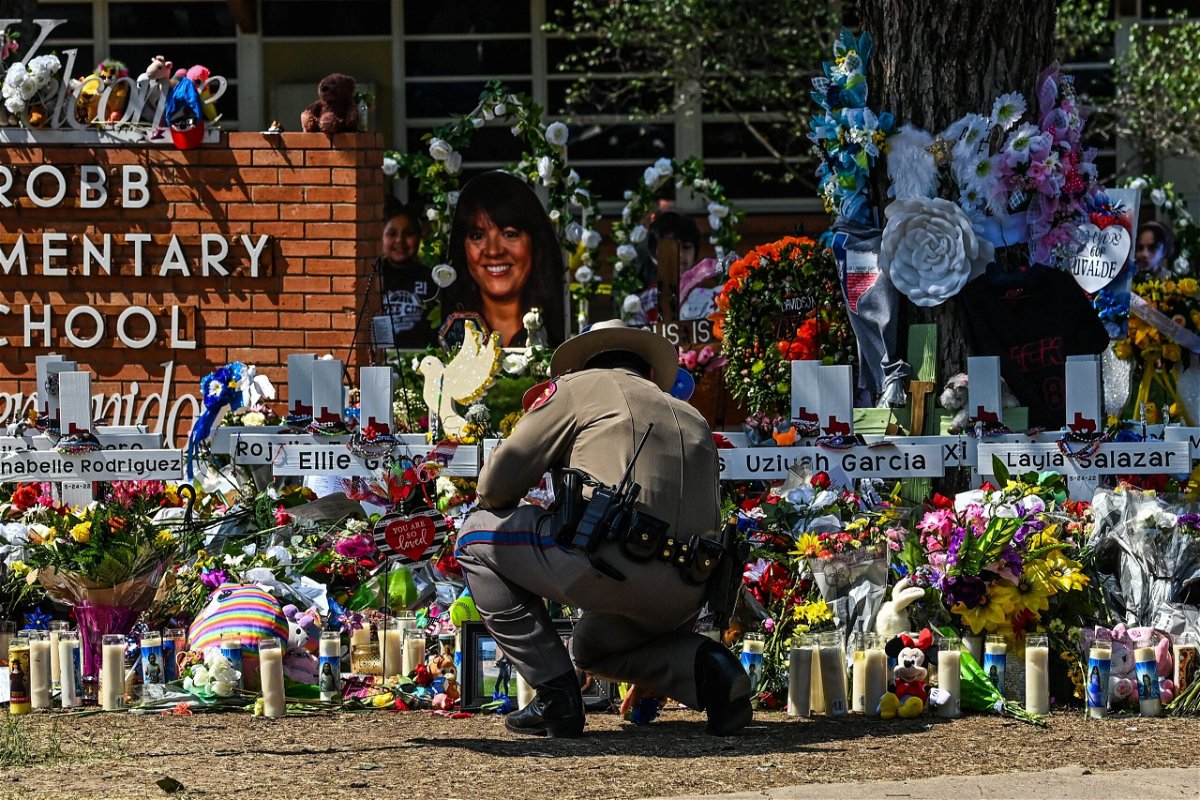 <i>Chandan Khanna/AFP/Getty Images</i><br/>A police officer clears the makeshift memorial before the visit of President Joe Biden at Robb Elementary School in Uvalde